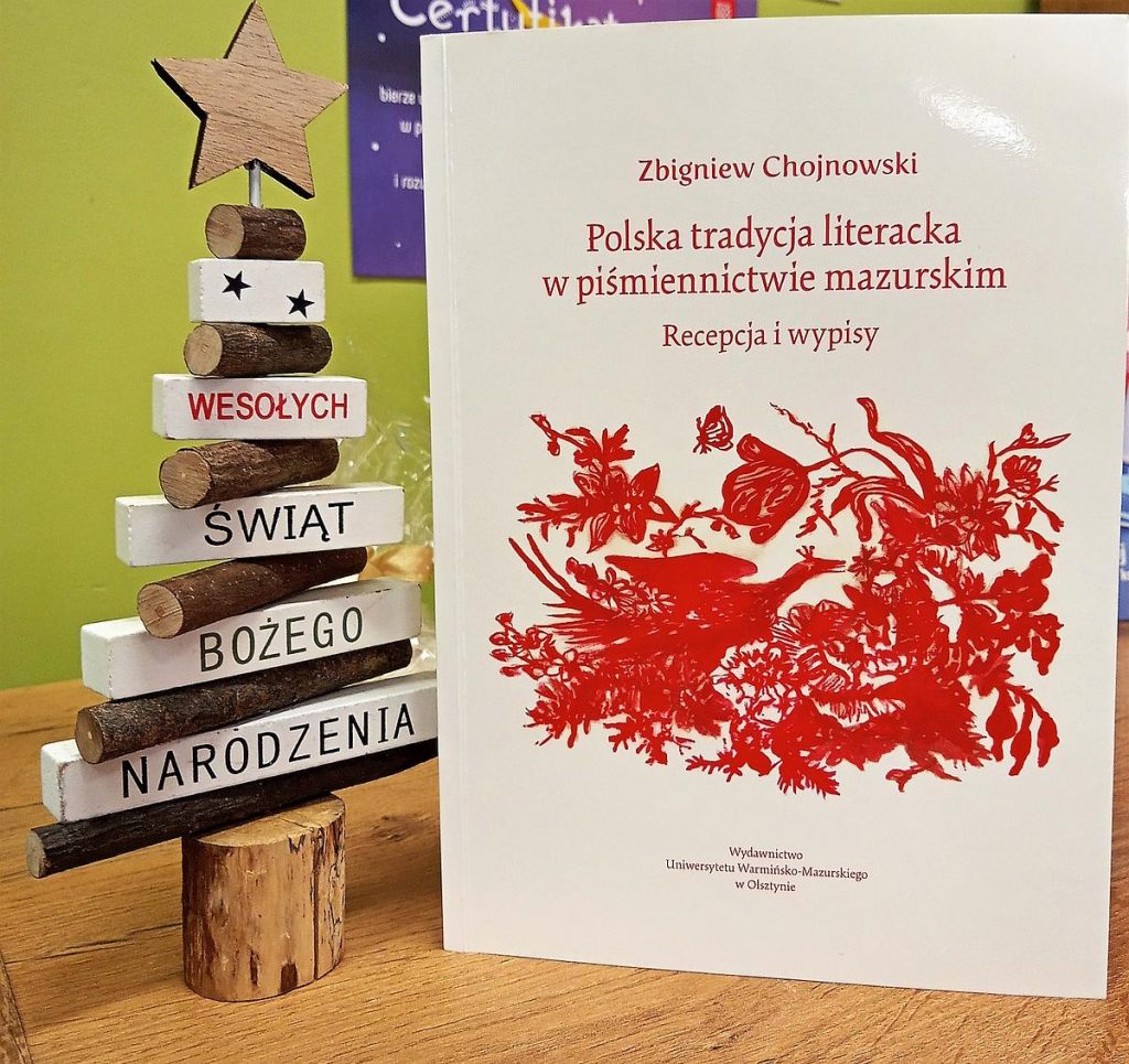 Na zdjęciu widać książkę oraz choinkę.