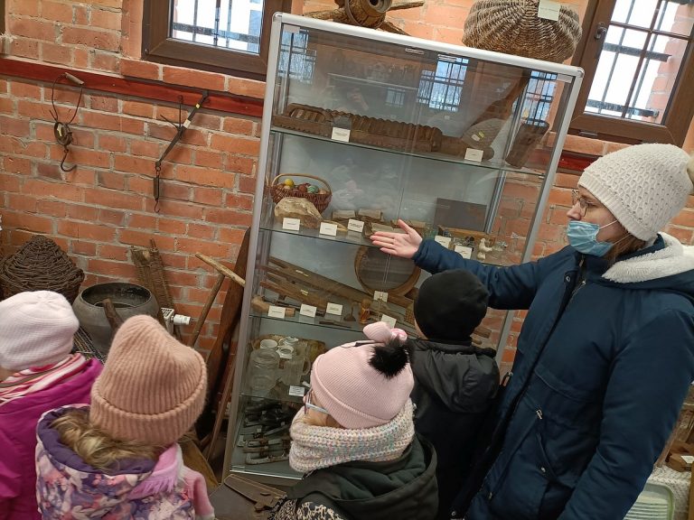 Pani pokazuje dzieciom eksponaty w muzeum.