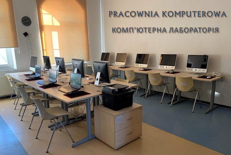 Komputery na stolikach i napis w dwóch językach: pracownia komputerowa