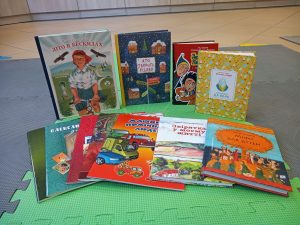 11 książek dla dzieci w języku ukraińskim ułożonych na podłodze w wypożyczalni biblioteki.