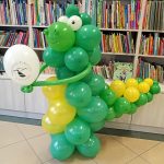 Dinozaur z balonów trzymający balon biblioteki.