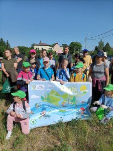 Grupa ludzi stoi w plenerze z plakatem „Czysta Gołdapa”