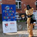 Miś w cylindrze przy rolapie z napisem „Cała Polska czyta dzieciom”.