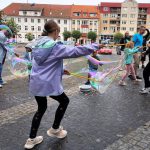 Dzieci puszczają bańki mydlane za pomocą kijków.