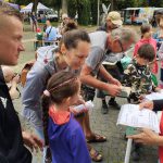 Dzieci i dorośli pochylają się nad książkami.