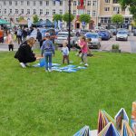 Na zdjęciu widzimy osoby bawiące się na trawie.