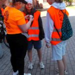 Na zdjęciu widzimy Panią, która przypina uczestnikom wydarzenia przypinkę odjazdowego bibliotekarza.