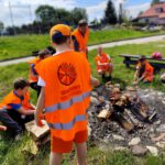 Na zdjęciu widzimy uczestników odjazdowego bibliotekarza piekących kiełbaski nad ogniskiem.