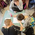 Troje chłopców wykonują prace przy stoliku