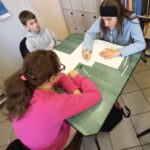 Troje dzieci wykonują prace przy stoliku