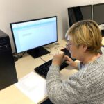 Uczestniczka warsztatów komputerowych 50+ ćwiczy pisanie tekstu w programie do pisania na komputerze stacjonarnym podczas zajęć w bibliotece.