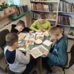 Czterech chłopców układają koraliki tworząc zakładkę do książki.