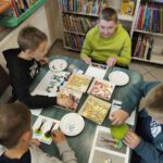 Czterech chłopców układają koraliki tworząc zakładkę do książki.