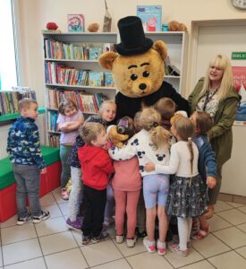 Dzieci przytulają misia w kapeluszu