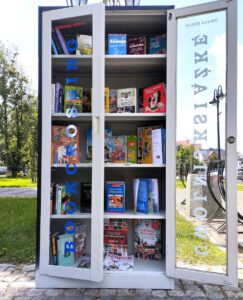 Szafa z otwartymi drzwiami wypełniona książkami.