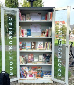 Otwarta szafa bookcrossingowa z poukładanymi woluminami.