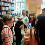 Na zdjęciu widzimy uczestników wycieczki oglądających gogle VR i księgozbiór regionalny.