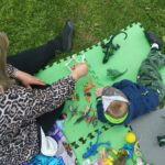 Na zdjęciu widzimy uczestników wydarzenia bawiących się dinozaurami.