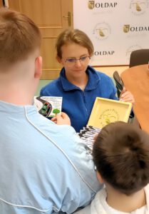 Na zdjęciu pracownik Biblioteki Publicznej w Gołdapi rozdaje dzieciom upominki ze skrzyneczki.