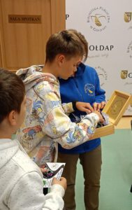 Zdjęcie przedstawia dziecko, które wybiera sobie upominek ze skrzyneczki.