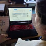 Laptop na którym pracuje młodzież w tle widać prowadzącego.