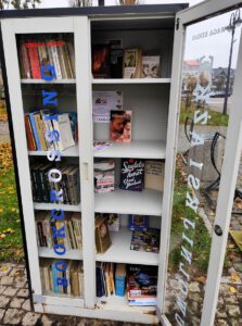 Szafa otwarta z prawymi drzwiami, na półkach widać ustawione książki.