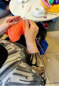 Dłonie które trzymają druty i swoją prace.