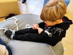 Chłopak siedzący na pufie robi swoją pracę.