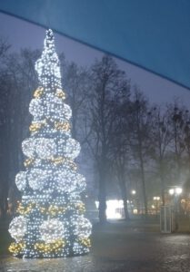 Na zdjęciu widzimy dużą świecącą choinkę, a w tle stoi szafa bookcrossingowa.