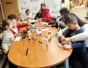 Grupa uczestników z warsztatu siedząca za stołem.