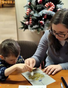 Kobieta w okularach wykonująca z dzieckiem kartkę.