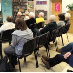 Uczestnicy spotkania siedzący na krzesłach.