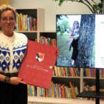 Autorka książek trzymająca otrzymany prezent w postaci teki.