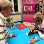 Autorka składająca autograf w książce dla uczestniczki spotkania.