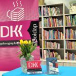 Książka, kwiaty ustawione na stoliku w tle rolap DKK.