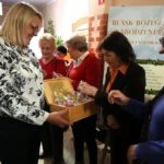 Na zdjęciu widzimy uczestników wernisażu wystawy częstujących się kolorowymi bombkami.