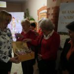 Na zdjęciu widzimy uczestników wernisażu wystawy częstujących się kolorowymi bombkami.