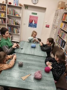Dzieci tworzą choinki z włóczki.