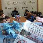 Na pierwszym planie zdjęcia widoczne podziękowania w drugim planie dzieci przy stole.