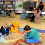 Dzieci przy stole układają klocki lego.