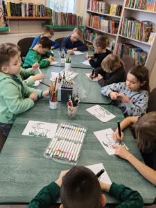 Grupa dzieci tworzy pracę . W tle widać regały z książkami.
