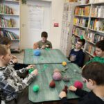 dzieci tworzą czapeczki z włóczki.