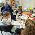 Pani policjantka rozdaje dzieciom kolorowanki