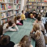 Chłopiec czyta dzieciom bajkę kamishibai