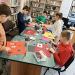 dzieci robią białe bałwanki z kartki i korka.