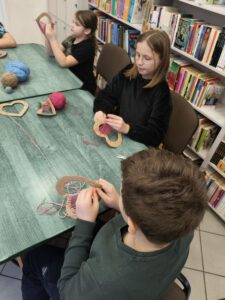 Dzieci wykonują prace plastyczne, wyszywają nicią.