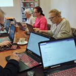 Na zdjęciu widzimy uczestników spotkania przeglądających na komputerach biblioteczną stronę internetową.