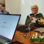 Na zdjęciu widzimy uczestnika spotkania pracującego na urządzeniu elektronicznym.