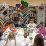 Zdjęcie przedstawia dzieci siedzące przy stole, wykonujące prace twórcze.