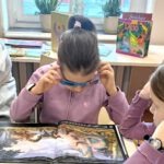 Zdjęcie przedstawia dziewczynkę w okularach 3d oglądającą książkę.